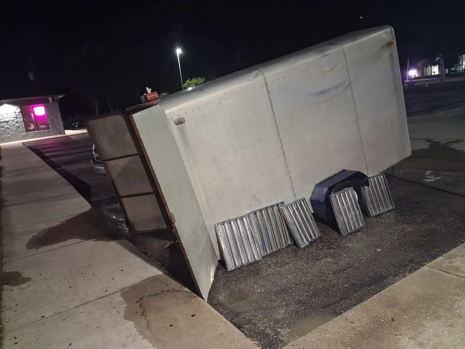 A commercial hood section and a row of baffle filters stood out on a car park at night, lined up on the tarmac ready to be washed.